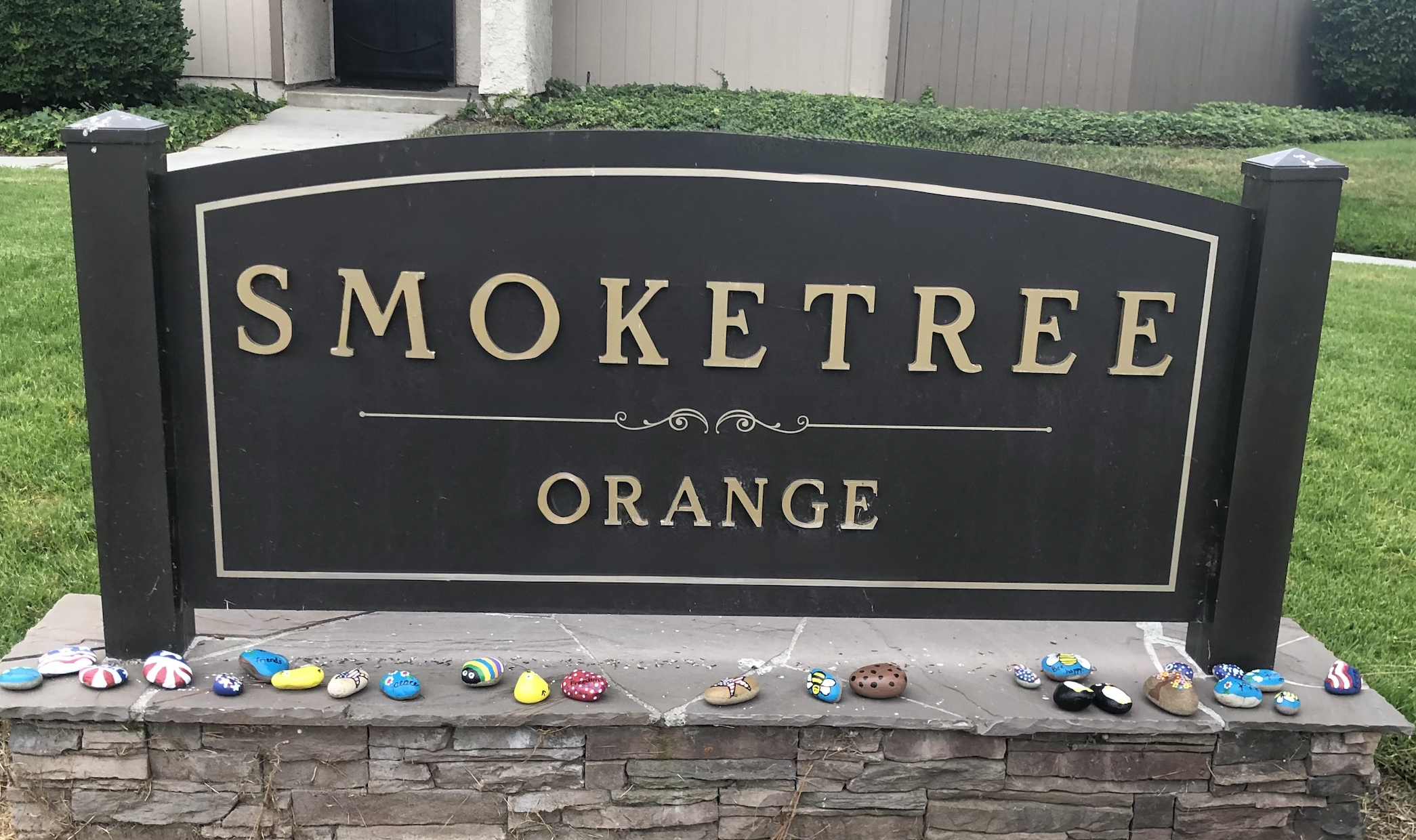 Smoketree Orange landmark sign with colorful rocks along the bottom.